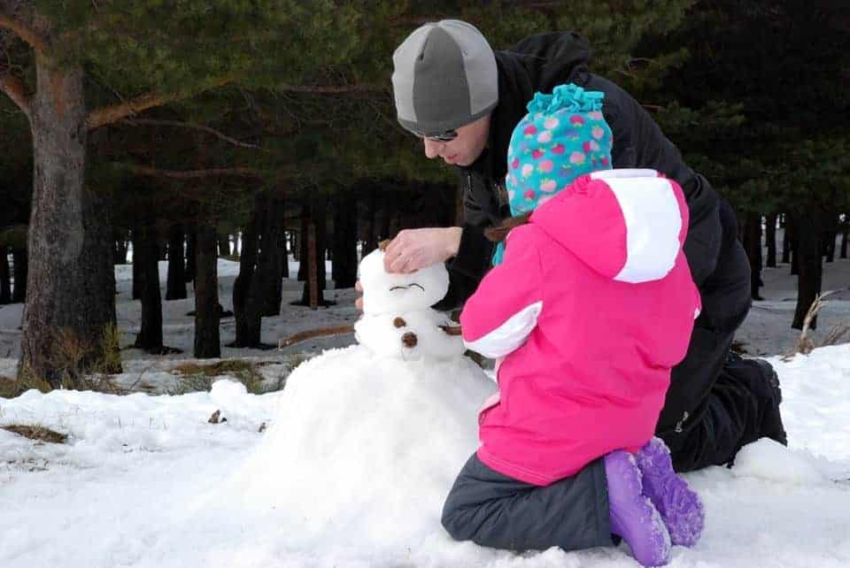 La peque con papá haciendo un muñeco de nieve