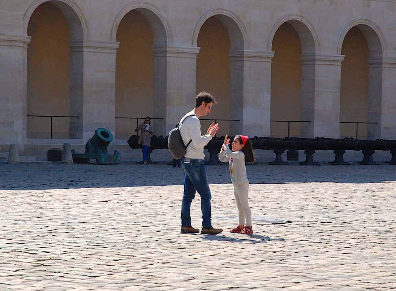 La peque y el papá juegan a un juego de palmas en el patio de Les Invalides, en Paris